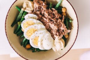 Delicious protein-packed bowl featuring tuna, boiled eggs, green beans, and hummus.